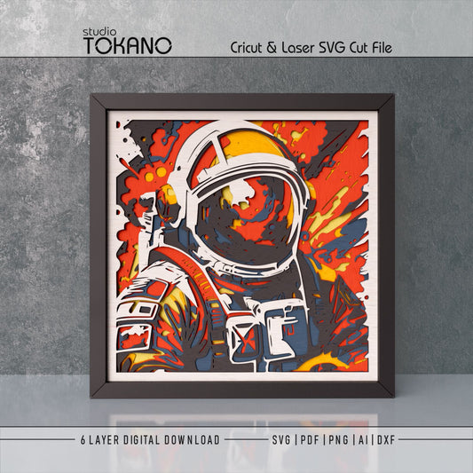 Framed astronaut layered wall art shown as a bold space papercut design with fiery colors and 3D depth.