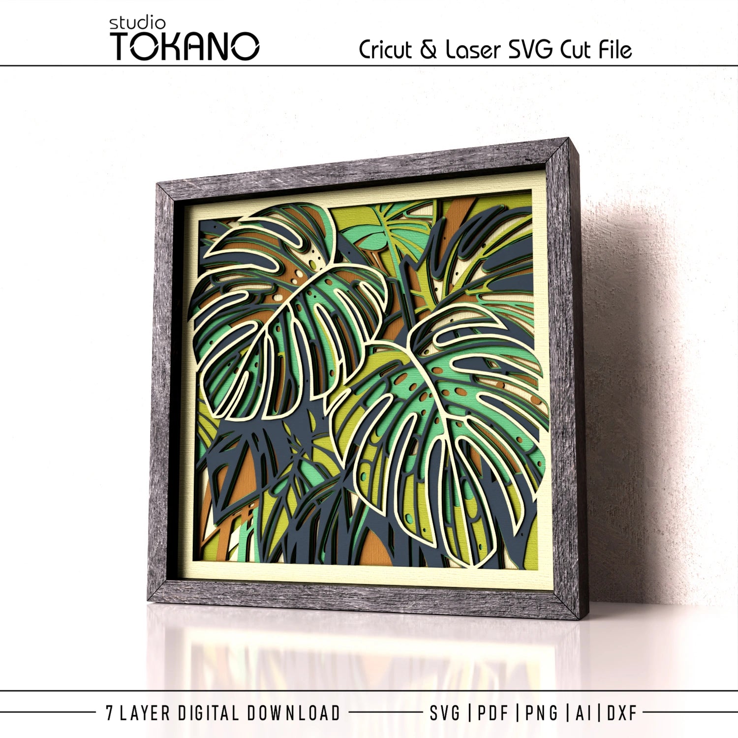 Digital product preview of a 7-layer SVG cut file featuring layered tropical monstera leaves. The artwork is displayed in a dark gray wooden frame, leaning against a white wall.